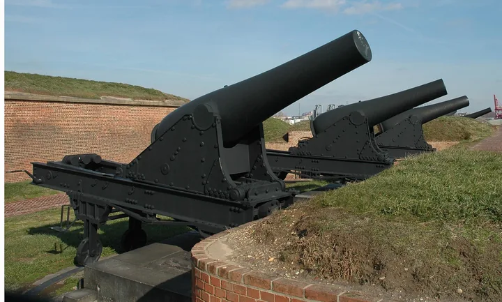Two huge black Rodman cannons on the grassy outer battery under a blue sky