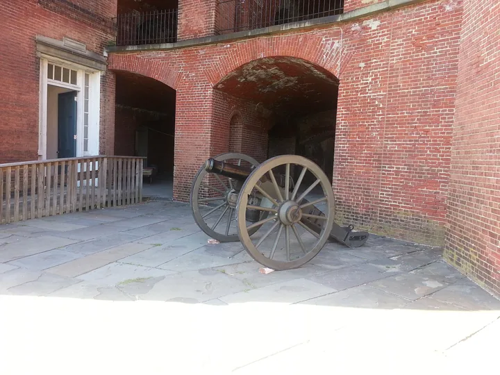A field gun on a wooden carriage inside a brick casemate with an arched opening