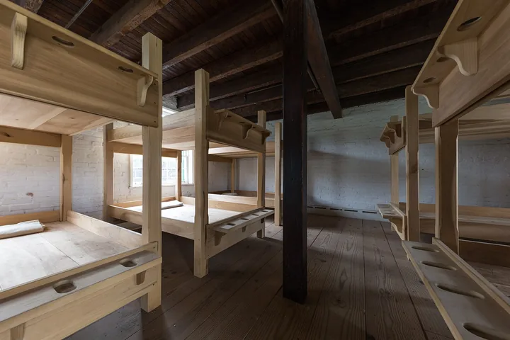 Rows of pale wooden double bunks in a plain room of the restored enlisted men's barracks
