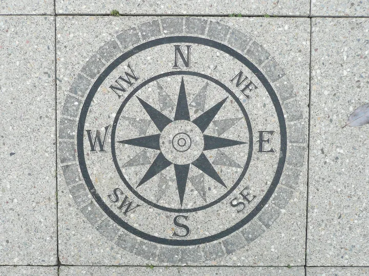 A stone compass rose with the eight points of the wind set into grey paving