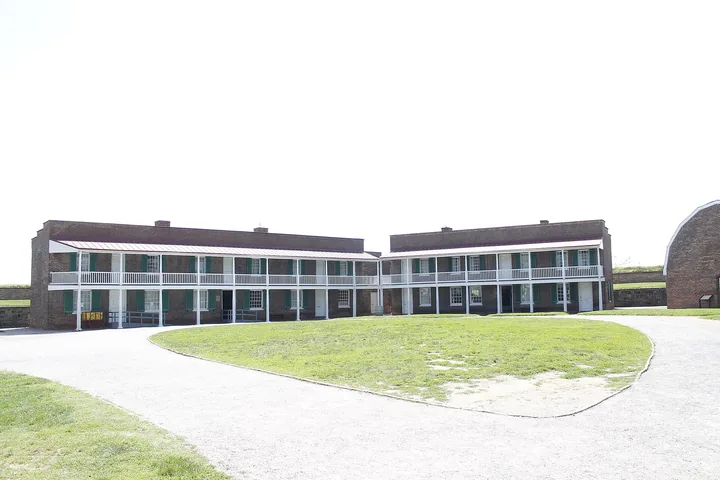 A long two-storey brick barracks with a wide paved path curving past a lawn