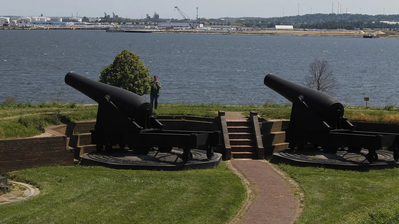 Two black Rodman cannons on iron carriages on the outer battery, with the harbor behind
